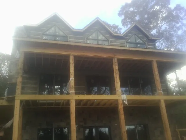 Dormers and porch framing on a large log home under construction — Roof Coating work by our crew in Larimer