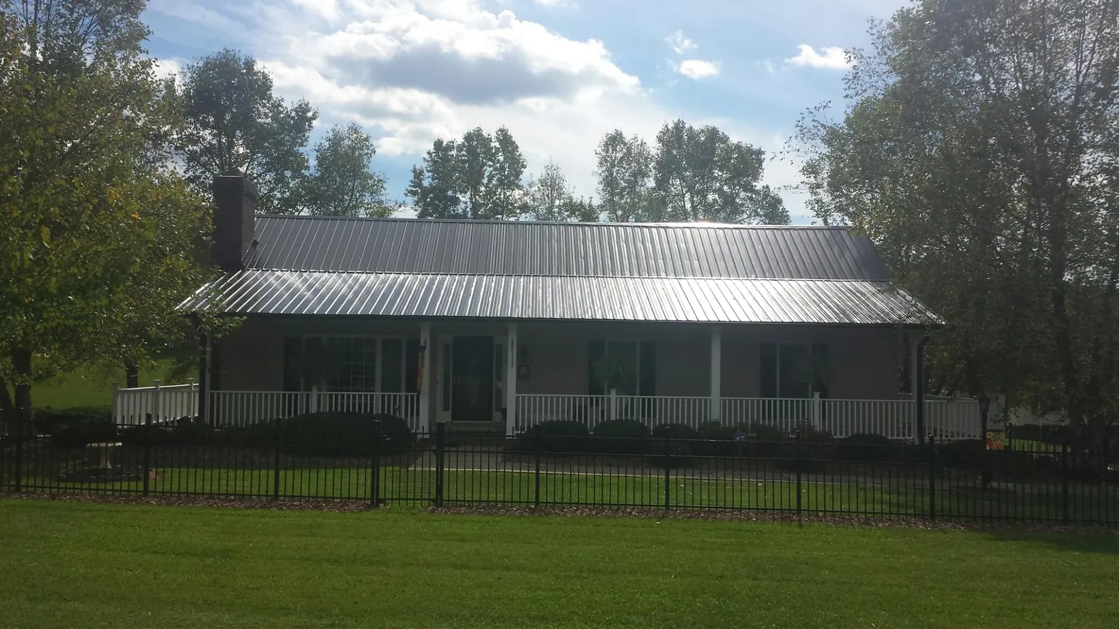 Gray metal roof on a brick ranch with a full width front porch — Gutter Guard Installation work by our crew in Larimer