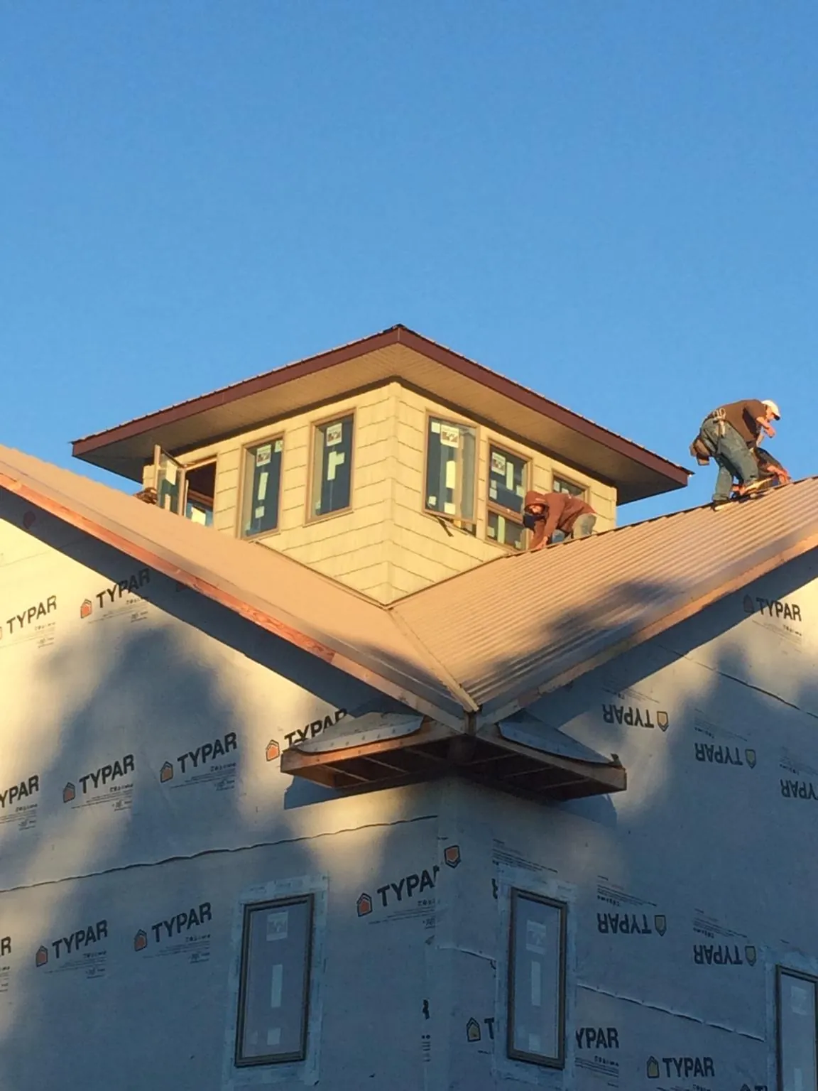 Roofers working around a rooftop cupola on a new metal roof at sunset — Roof Waterproofing in Larimer by Roofing Brothers